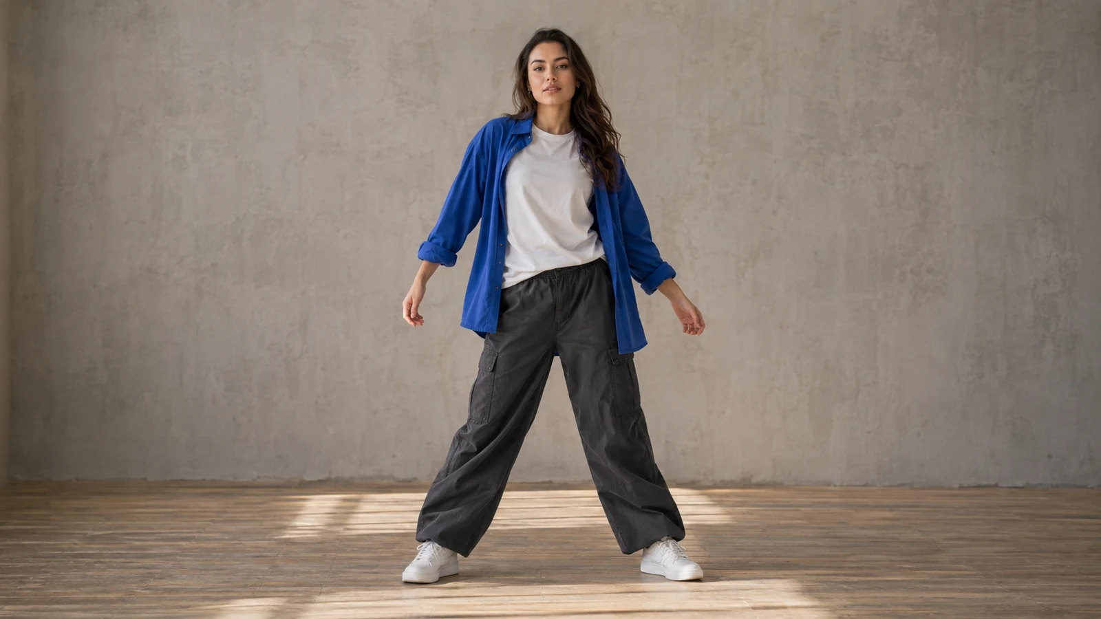 Woman in a blue overshirt standing in a studio, shown head to toe