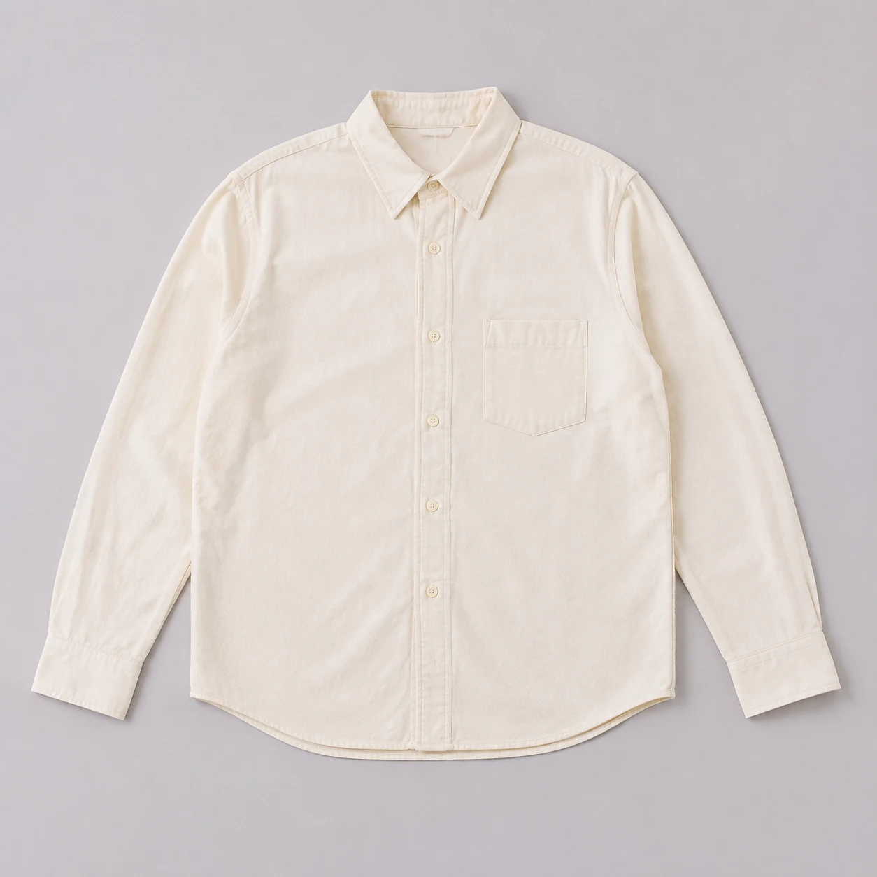 Ivory button-up shirt laid flat on a gray background